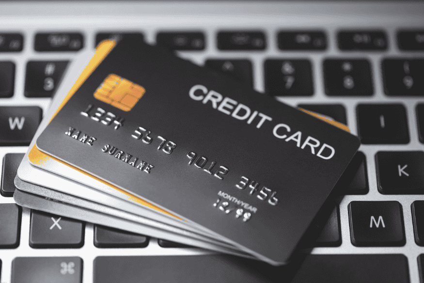 Stack of black and gold credit cards placed on a laptop keyboard